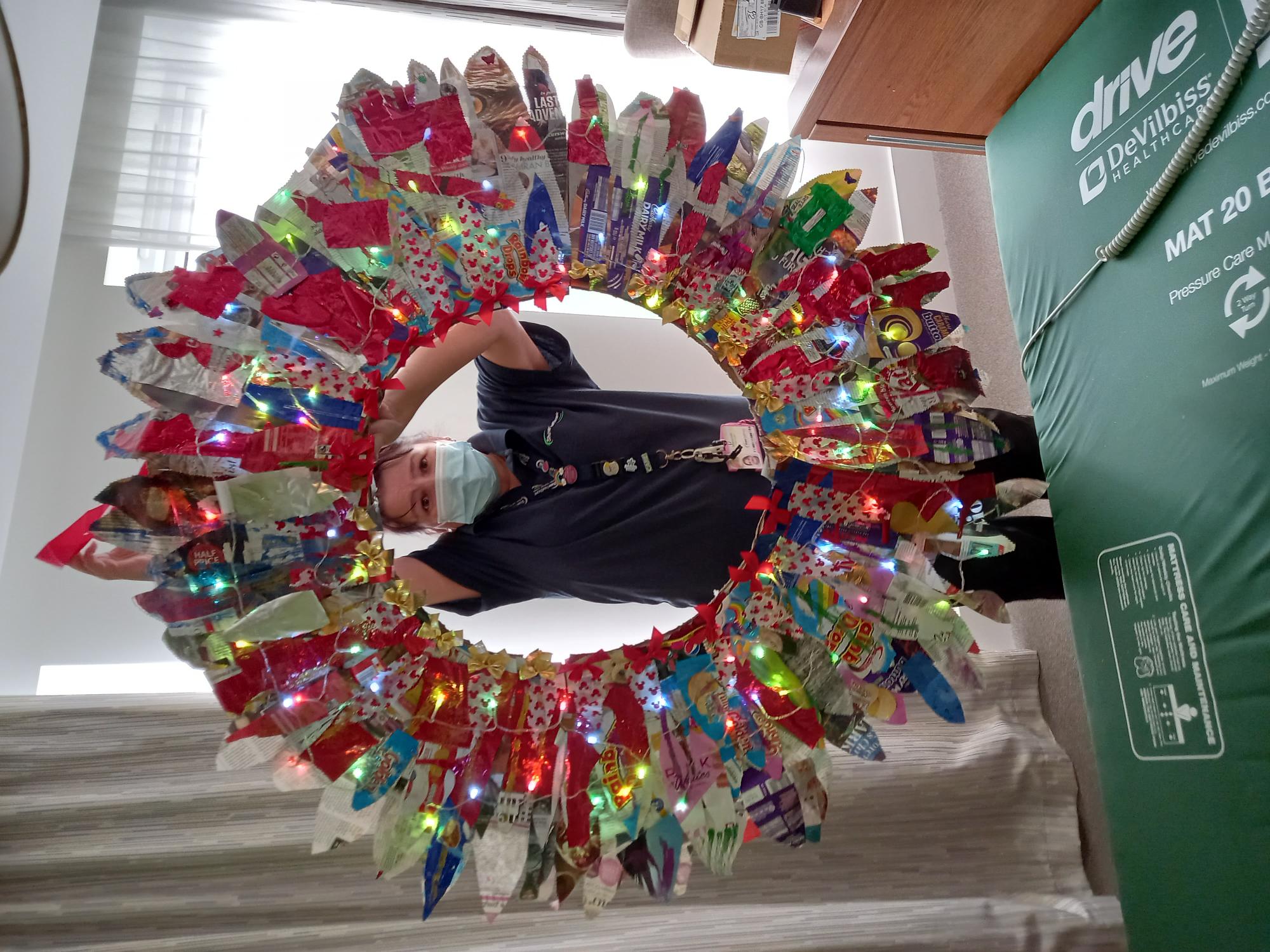employee holding up a wreath made out of recycling 