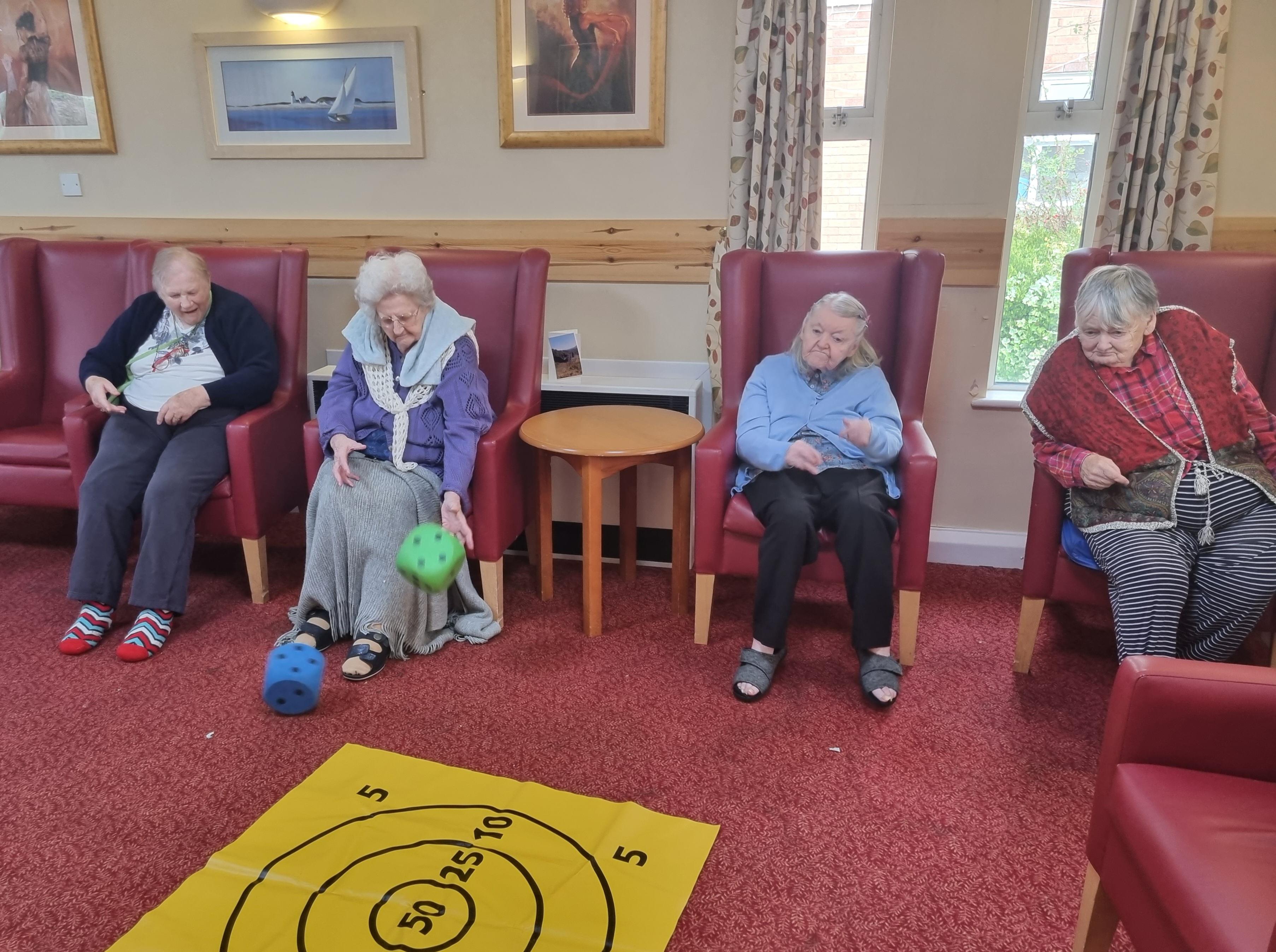 Ladies at Trenewydd throwing a dice as part of their exercise activity  