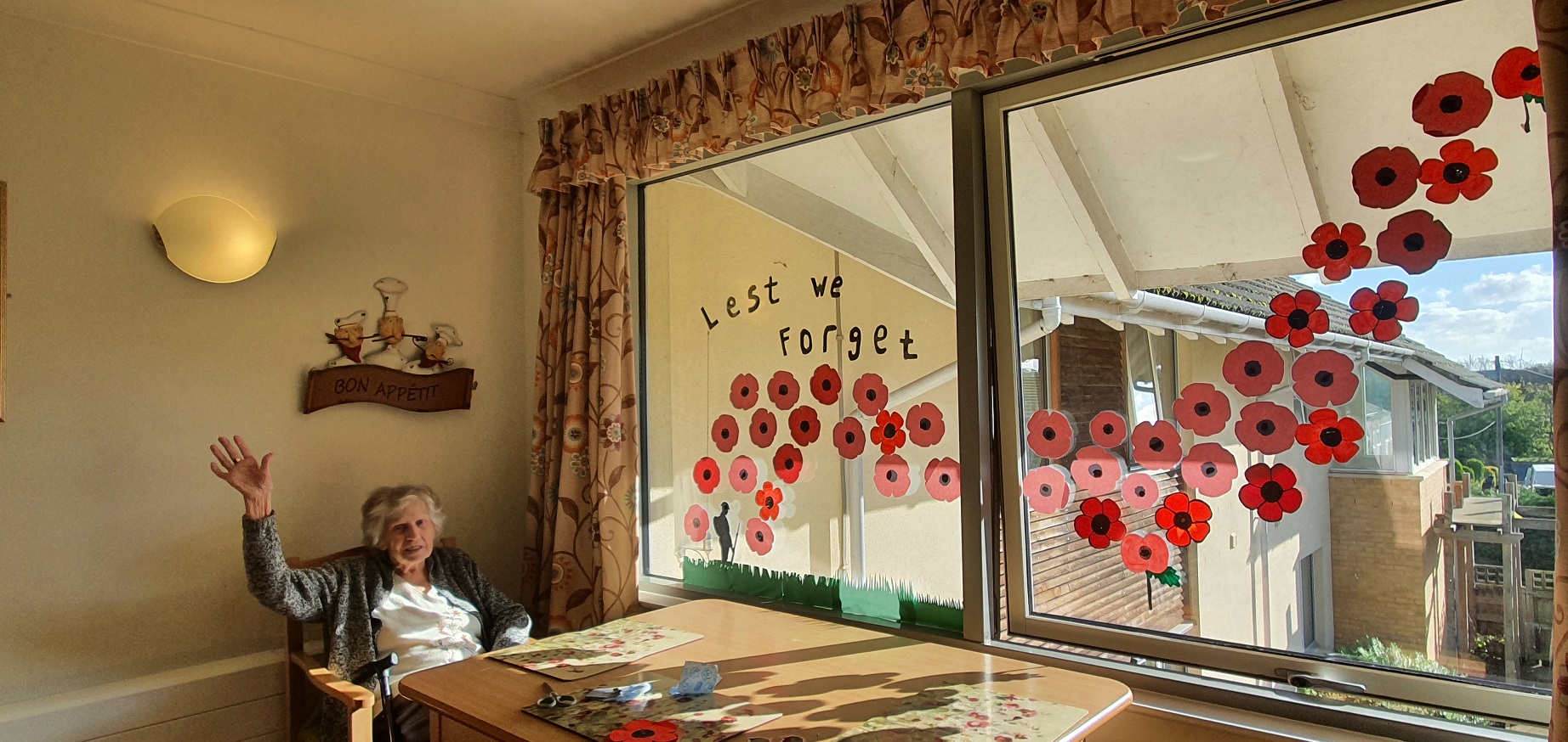 resident next to a window filled with poppy's saying 'Lest we forget'