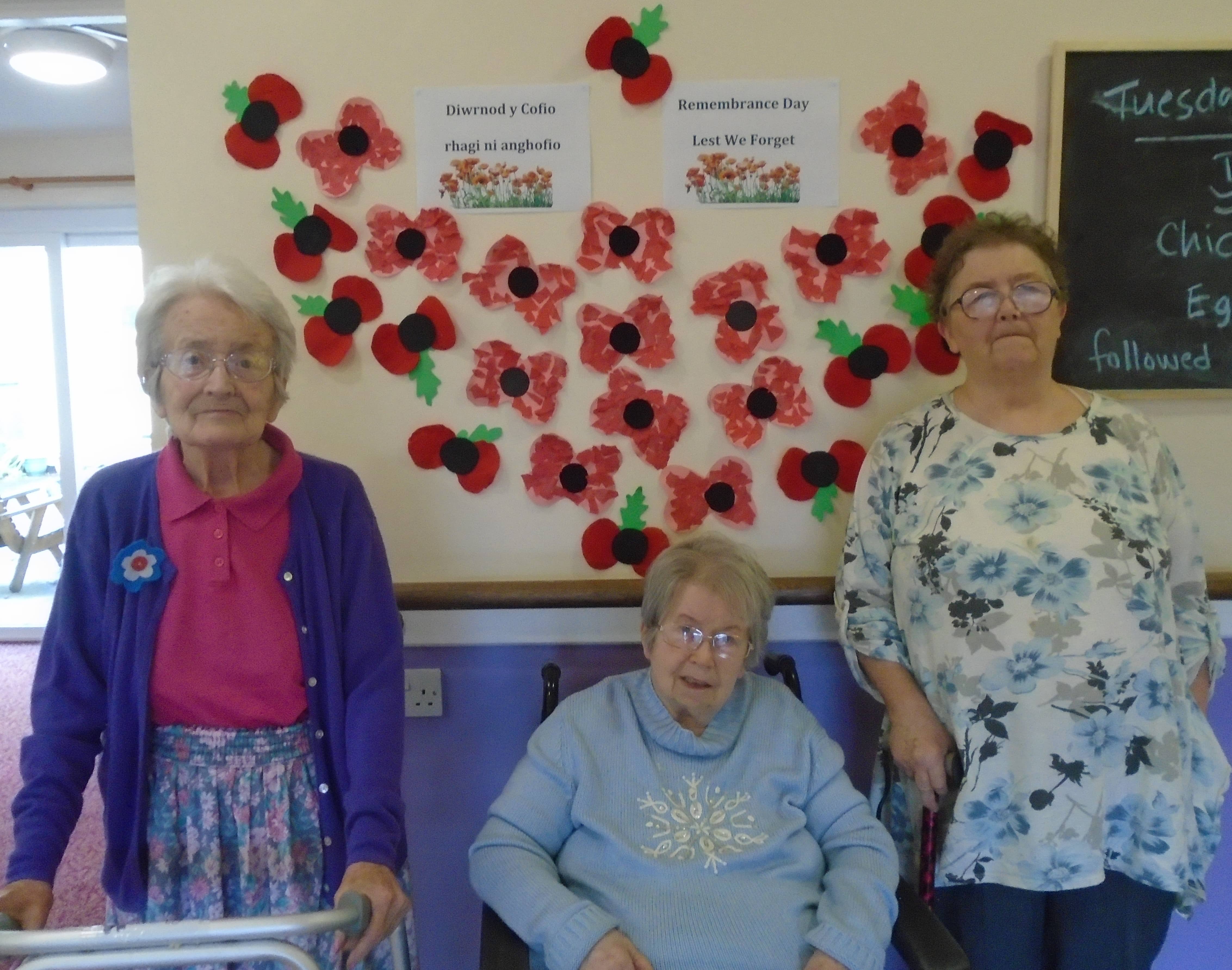three residents stood by the poppy wall that they made