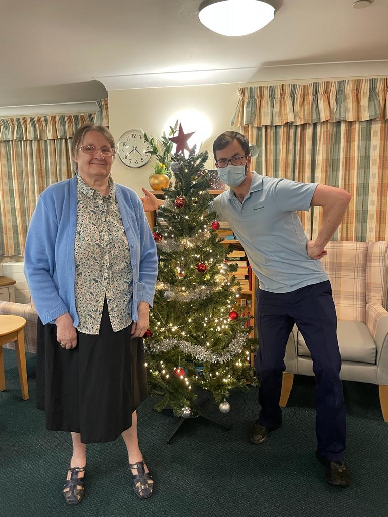 resident and employee standing by Christmas tree 