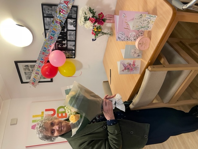 resident with cards and flowers at care home for birthday