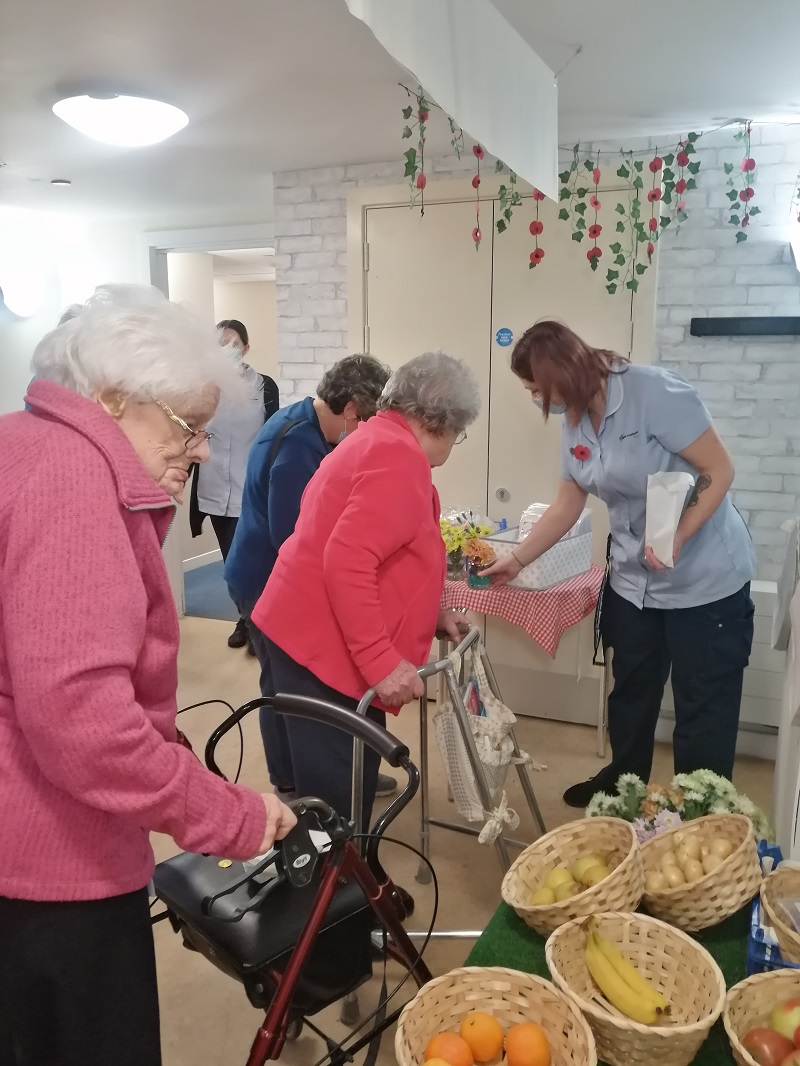 residnents at care home enjoying buying goods from the market
